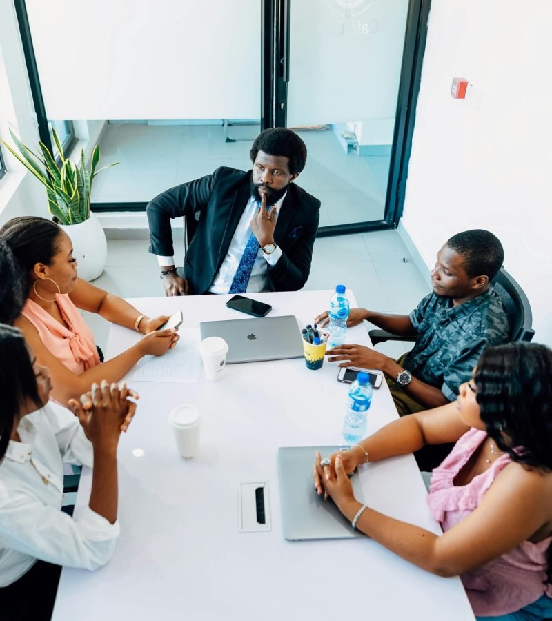 A group of professionals engaged in a business discussion around a table in a Lagos office.
